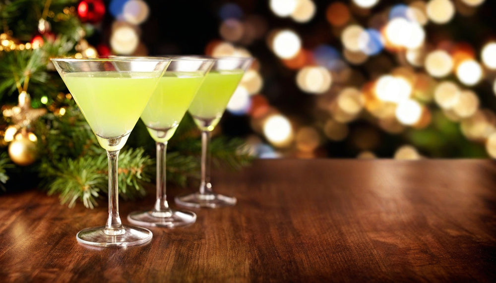 3 martini glasses with BeTini in it on a wood table with Christmas decorations in the background.